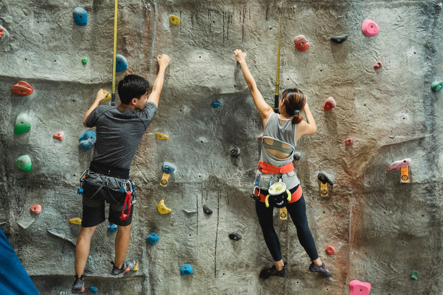 young fit sporty couple training on climbing wall