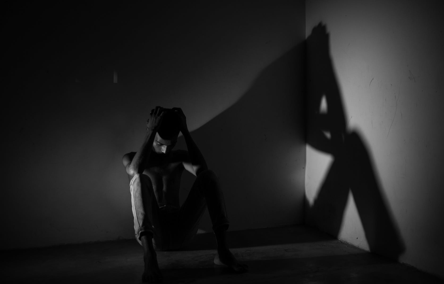 man sitting in darkness in room corner