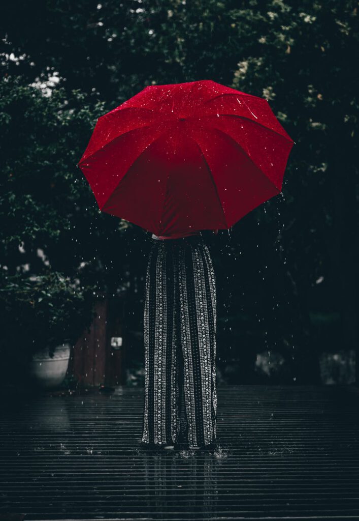 person standing using red umbrella