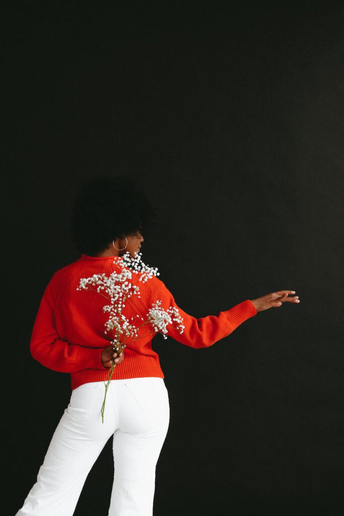 dancing black woman hiding flower behind back in studio