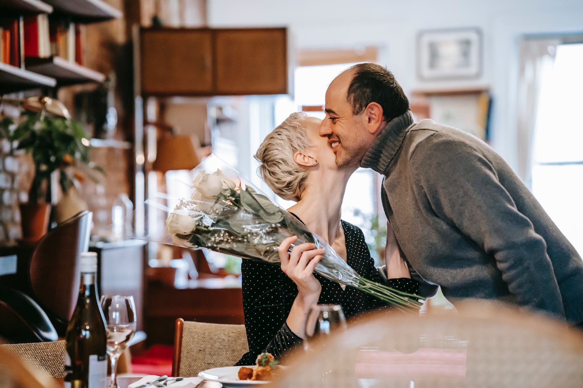 woman holding bouquet of flowers kissing a man